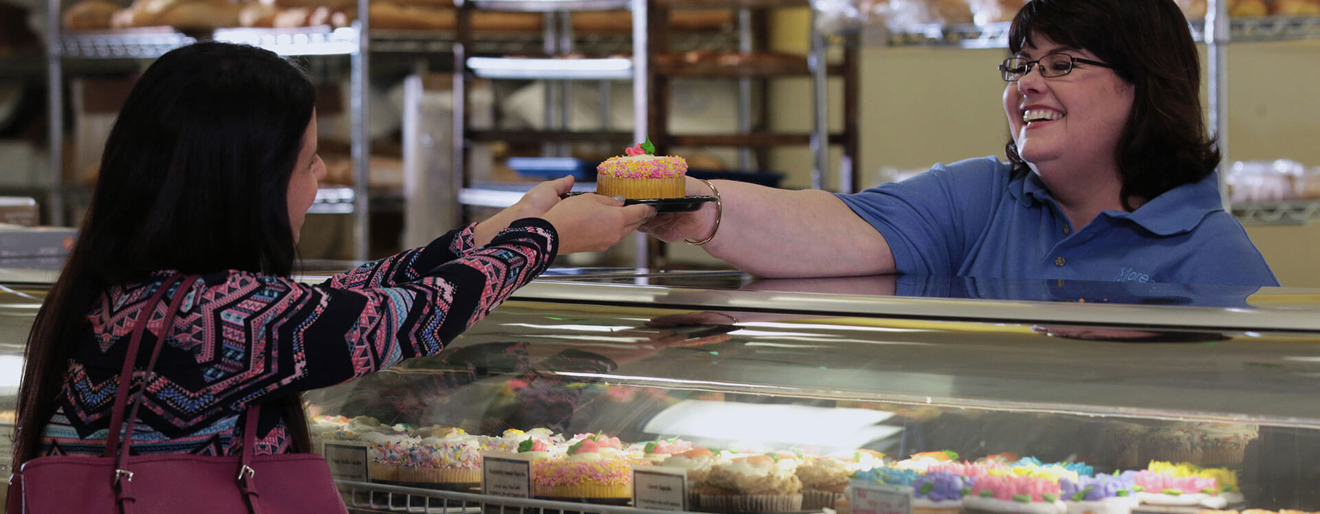 Susan handing cupcake to customer